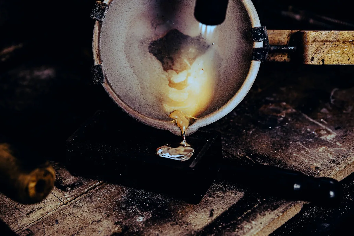 Molten metal glowing in a small crucible on a workbench