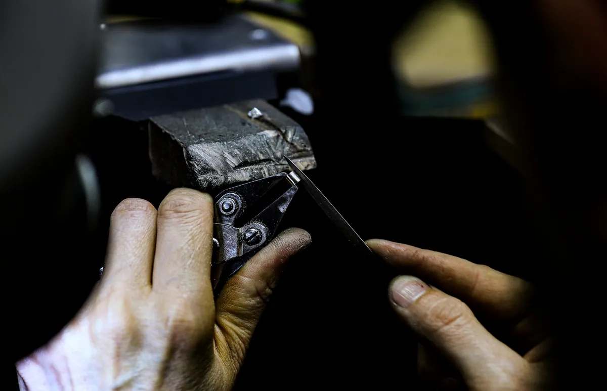 Hands filing a ring held in a bench vice