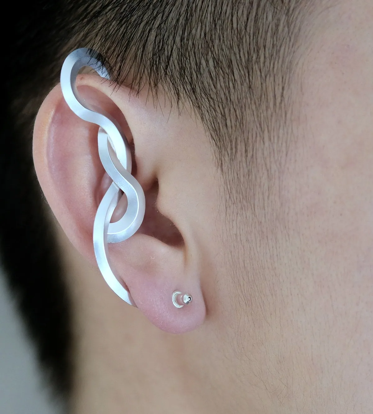 A sculpted silver ear cuff curving along the rim of an ear